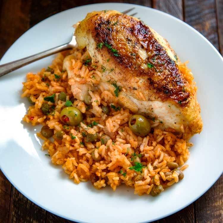 A plate of rice, chicken, green olives are visible